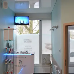 Wnętrze salonu kosmetycznego: recepcja z podświetlaną witryną, okno z napisem 'Manicure Pedicure', telewizor z motywem pustynnym, minimalistyczny design.