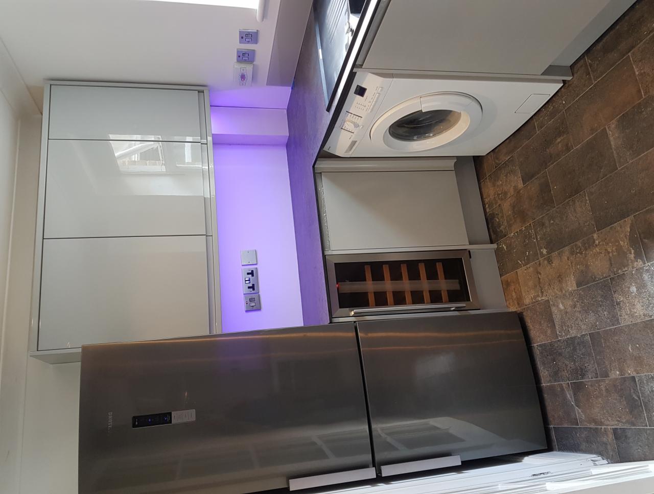 Nowoczesna kuchnia w Piotrkowie Trybunalskim z szarymi szafkami, zabudowaną pralką, lodówką ze stali nierdzewnej i podświetleniem LED.