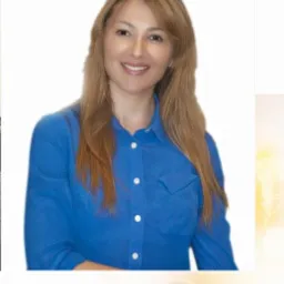 Portret uśmiechniętej kobiety w niebieskiej koszuli na jasnym tle, sugerujący profesjonalizm i zaufanie.