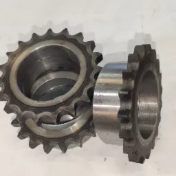 Dwie metalowe zębatki o różnej wielkości, ułożone na białym tle, z widocznymi śladami obróbki i zużycia.