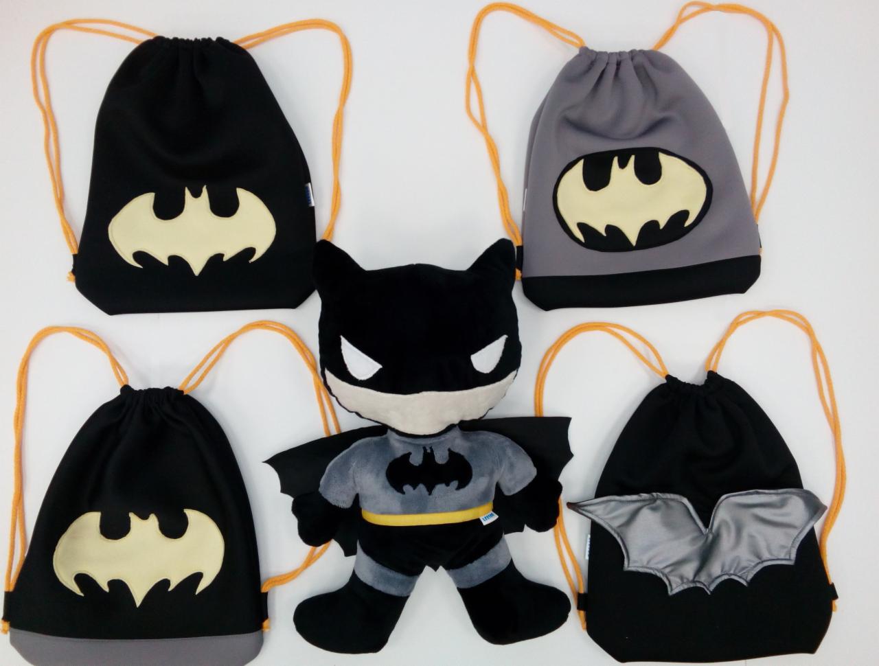 Cztery workoplecaki z motywem Batmana w różnych kolorach i pluszowa zabawka Batmana na białym tle.