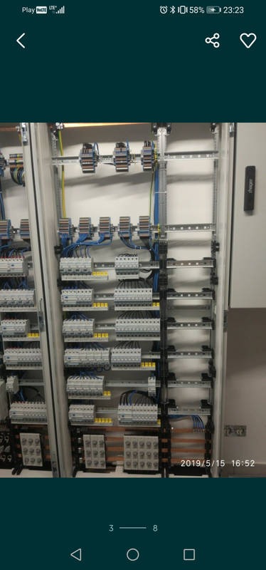 Rozdzielnica elektryczna z zainstalowanymi bezpiecznikami, przewodami i listwami zaciskowymi, widoczne kable w kolorze niebieskim i żółtym.