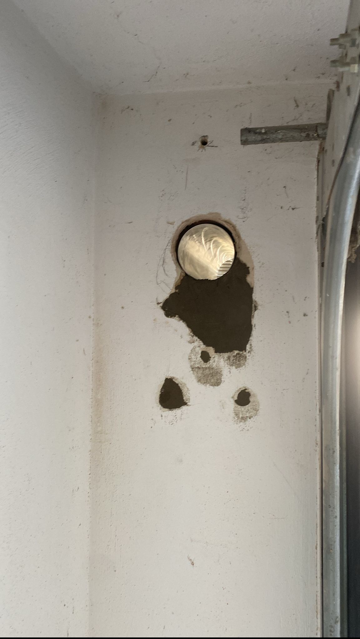 Otwór w ścianie po wykonaniu przejścia, z widocznymi śladami zaprawy i mniejszymi otworami obok.