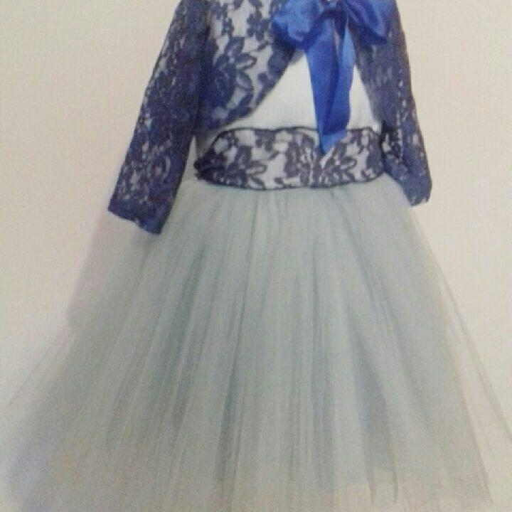 Dziecięca sukienka balowa z tiulowym dołem i koronkowym bolerkiem w kolorze granatowym, ozdobiona satynową kokardą.