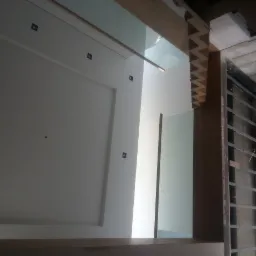 Ściana z gładzią, widoczne czarne punkty na ścianie, drewniane wykończenia sufitu i konstrukcja metalowa na ścianie bocznej w trakcie remontu.