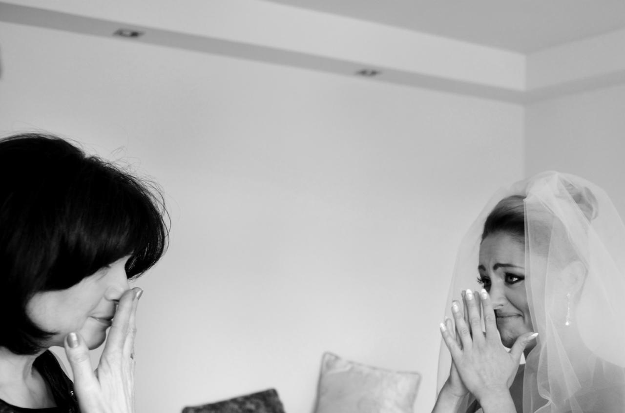 Czarno-białe zdjęcie wzruszonej panny młodej w welonie i jej matki, obie płaczące ze szczęścia w Kielcach, podczas przygotowań do ślubu.