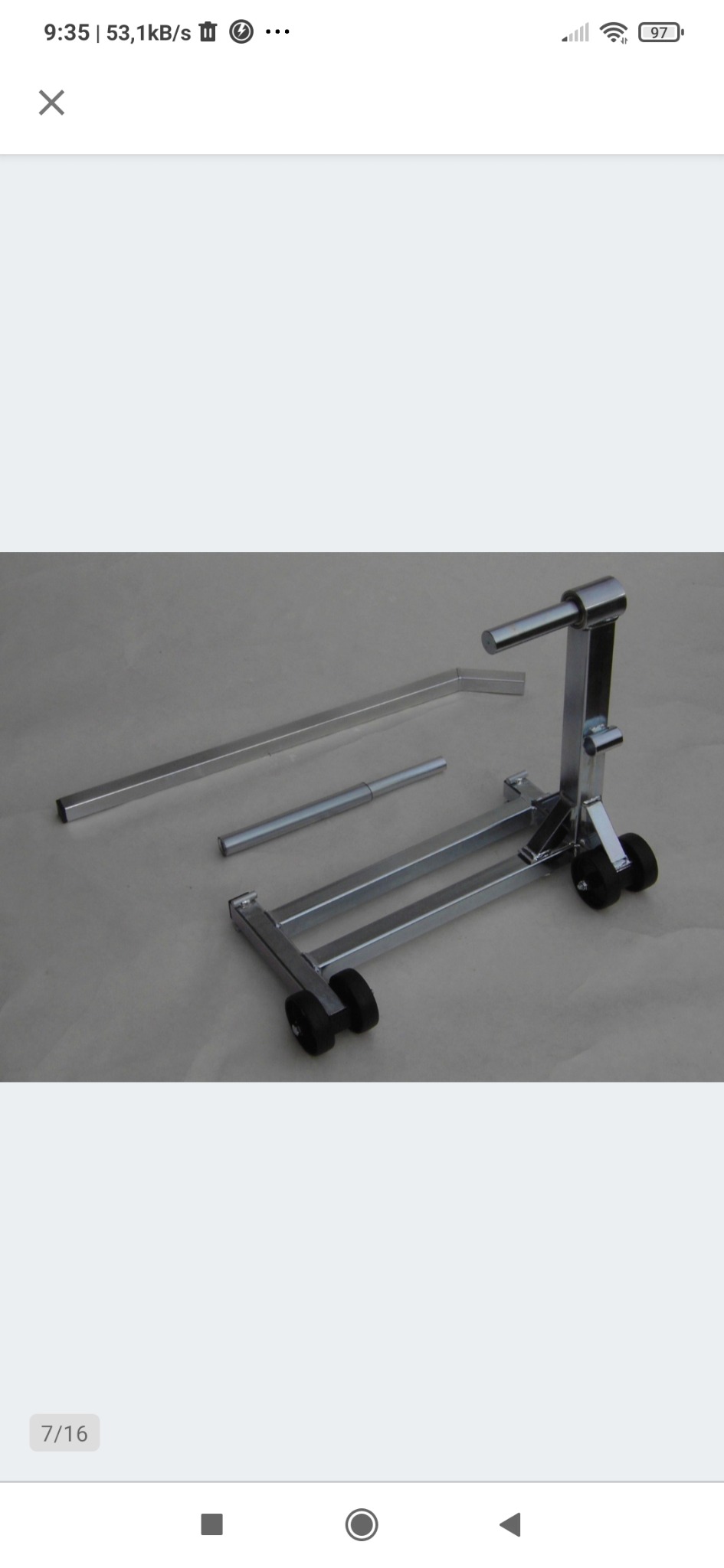 Srebrny, metalowy stojak motocyklowy z kółkami, rozłożony na części, leżący na szarym tle.