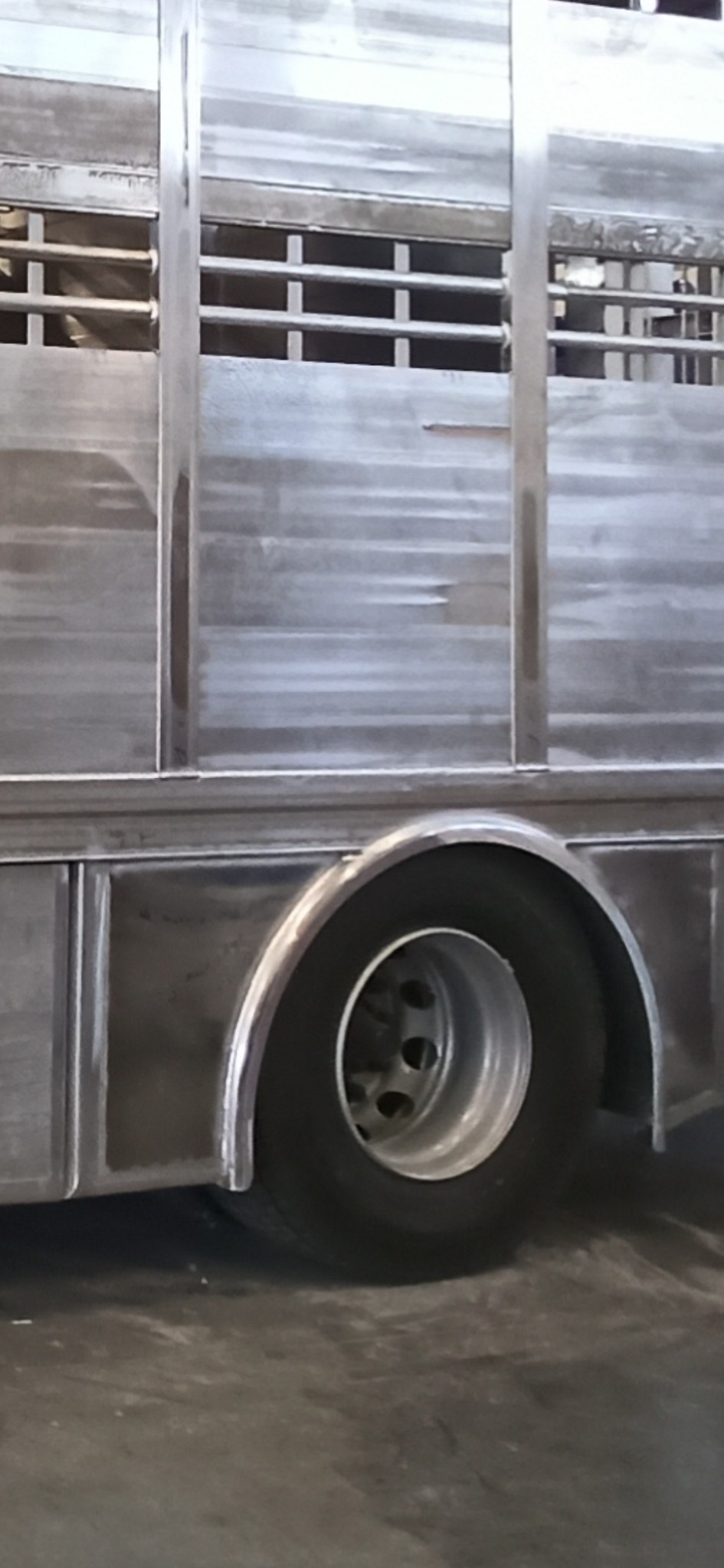 Aluminiowa przyczepa do transportu zwierząt z widocznymi spawami i elementami konstrukcyjnymi, prezentująca metalową ramę i koło.