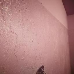 Gładzie Maszynowe Przemysław Kowalski - Ściana pokryta dekoracyjną, różową strukturą z widocznym otworem na instalację elektryczną i fragmentem sufitu w tle.