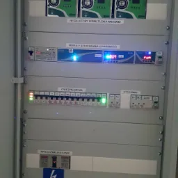 Rozdzielnica elektryczna z modułami sterowania cyfrowego, regulatorami oświetlenia widowni, zabezpieczeniami i wyłącznikiem głównym, widoczne oznaczenia i diody sygnalizacyjne.