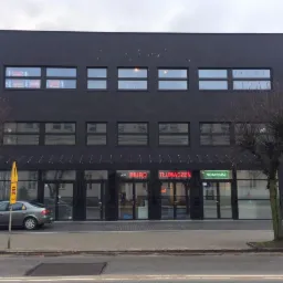 Fasada budynku z ciemnej cegły w Wejherowie, z neonowymi szyldami 'Biuro Tłumaczeń' i 'Notariusz' nad wejściami, widok z ulicy z zaparkowanym samochodem.