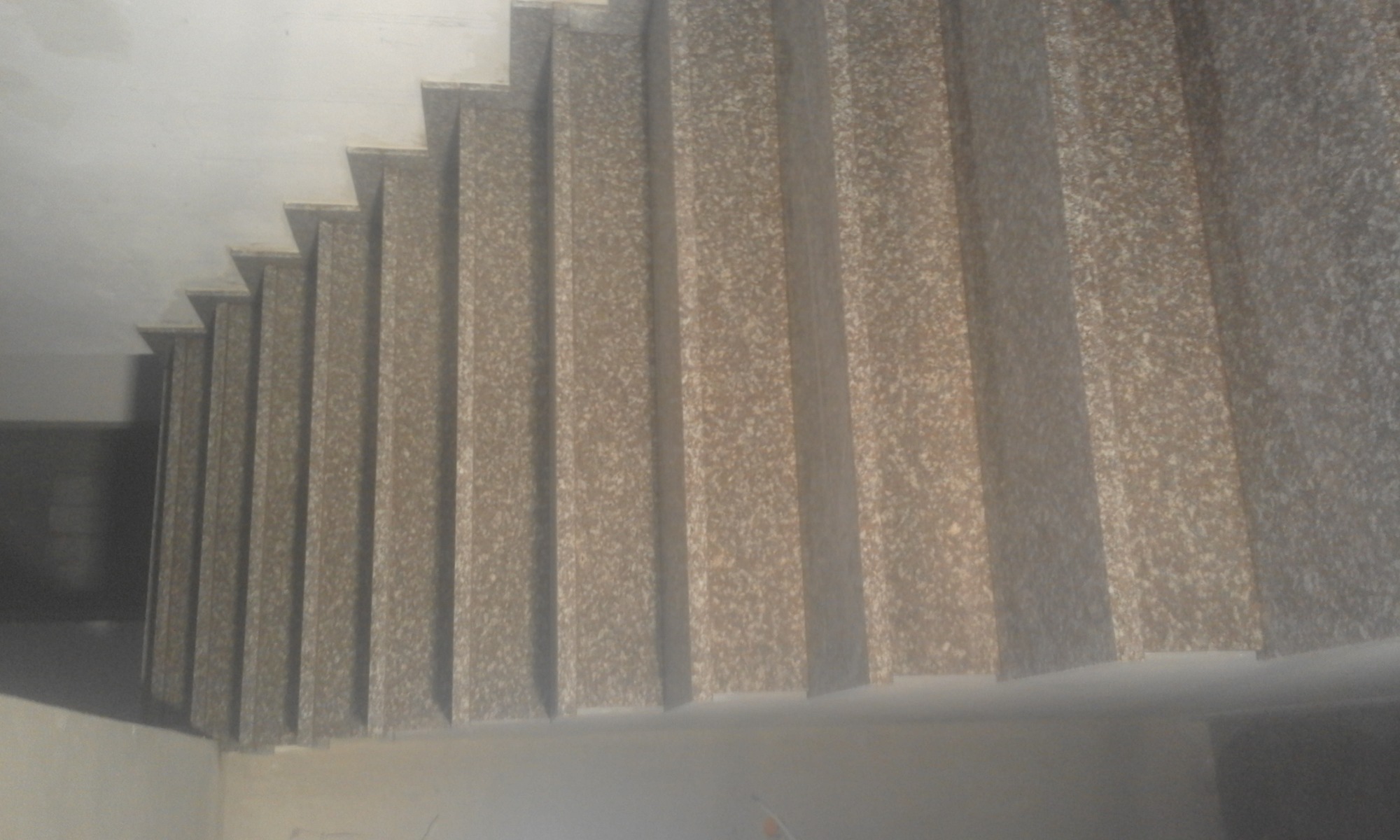 Wykończone schody z okładziną imitującą kamień, widok z dołu, z widocznym fragmentem sufitu i ściany.