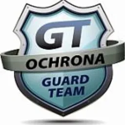 Logo firmy ochroniarskiej GT Ochrona Guard Team w kształcie tarczy z metalową wstęgą.