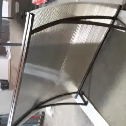 Zadaszenie z poliwęglanu oparte na metalowej konstrukcji w warsztacie, widoczne narzędzia i materiały w tle.