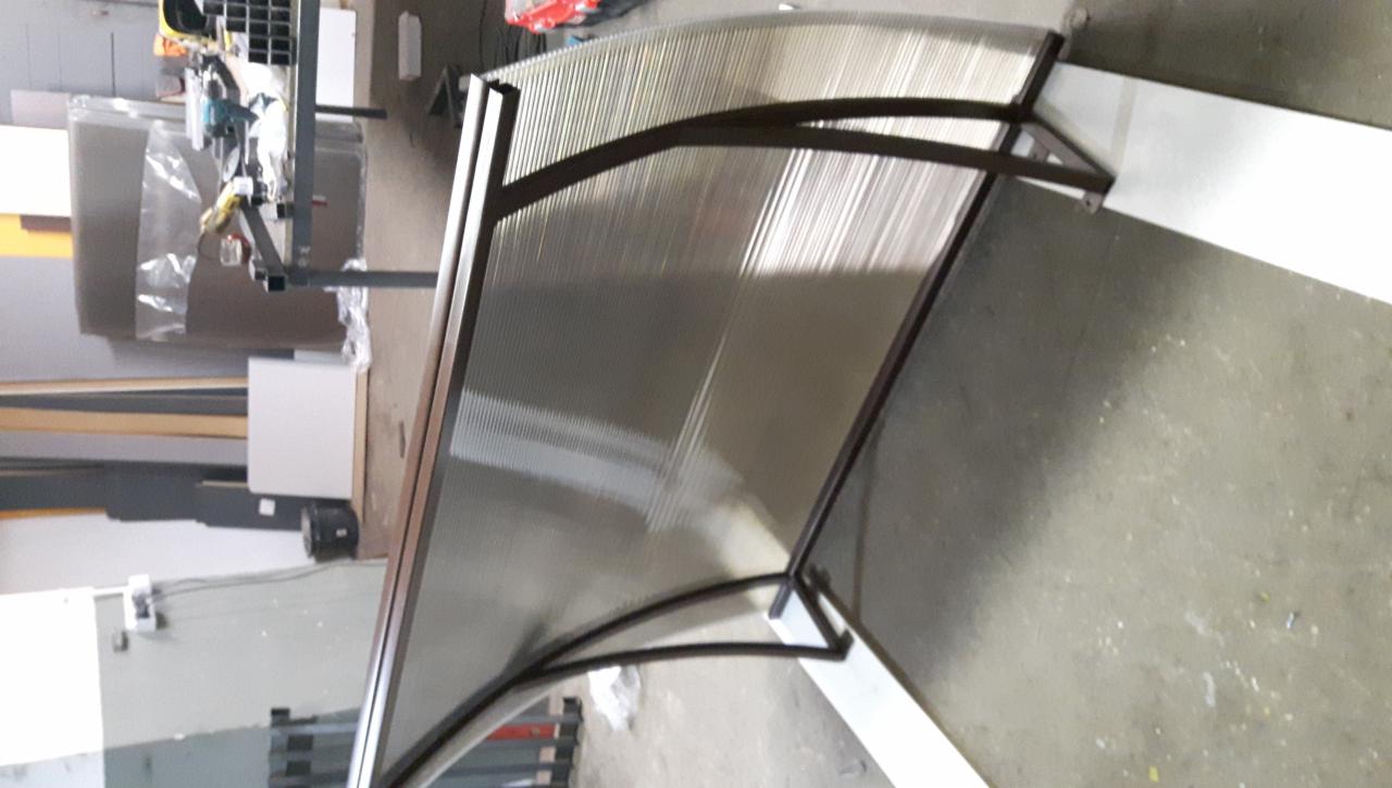 Zadaszenie z poliwęglanu oparte na metalowej konstrukcji w warsztacie, widoczne narzędzia i materiały w tle.