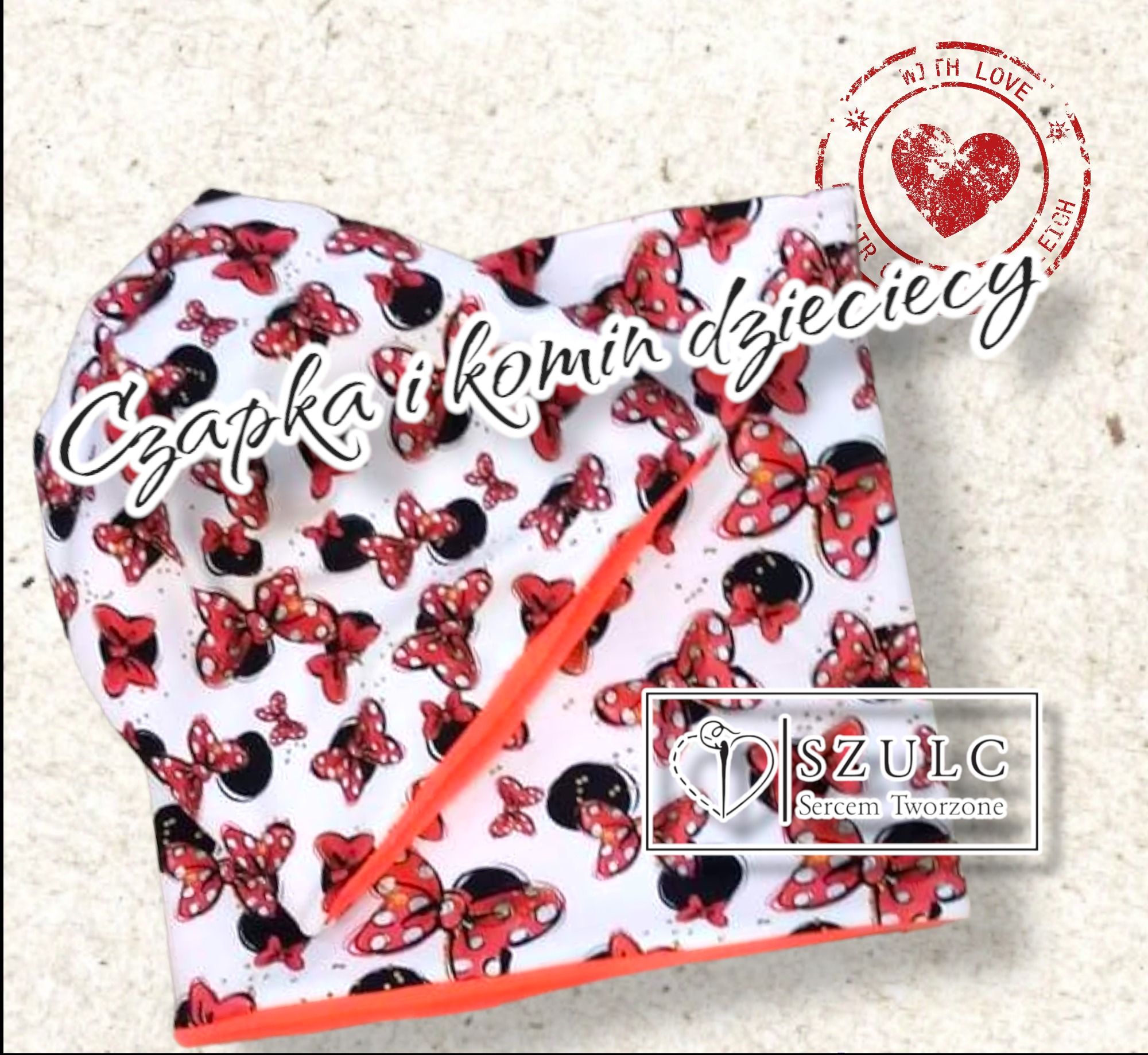 Dziecięcy komplet: czapka i komin z wzorem czerwonych kokardek na białym tle, wykończone pomarańczową lamówką, z widocznym logo firmy Szulc i stempelkiem 'With Love'.