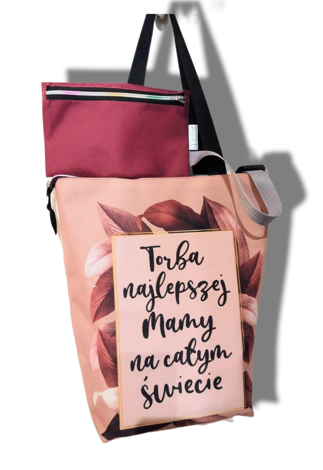 Torba shopper z motywem liści i napisem 'Torba najlepszej Mamy na całym świecie', z dodatkową bordową kieszenią na zamek i czarnymi uchwytami.