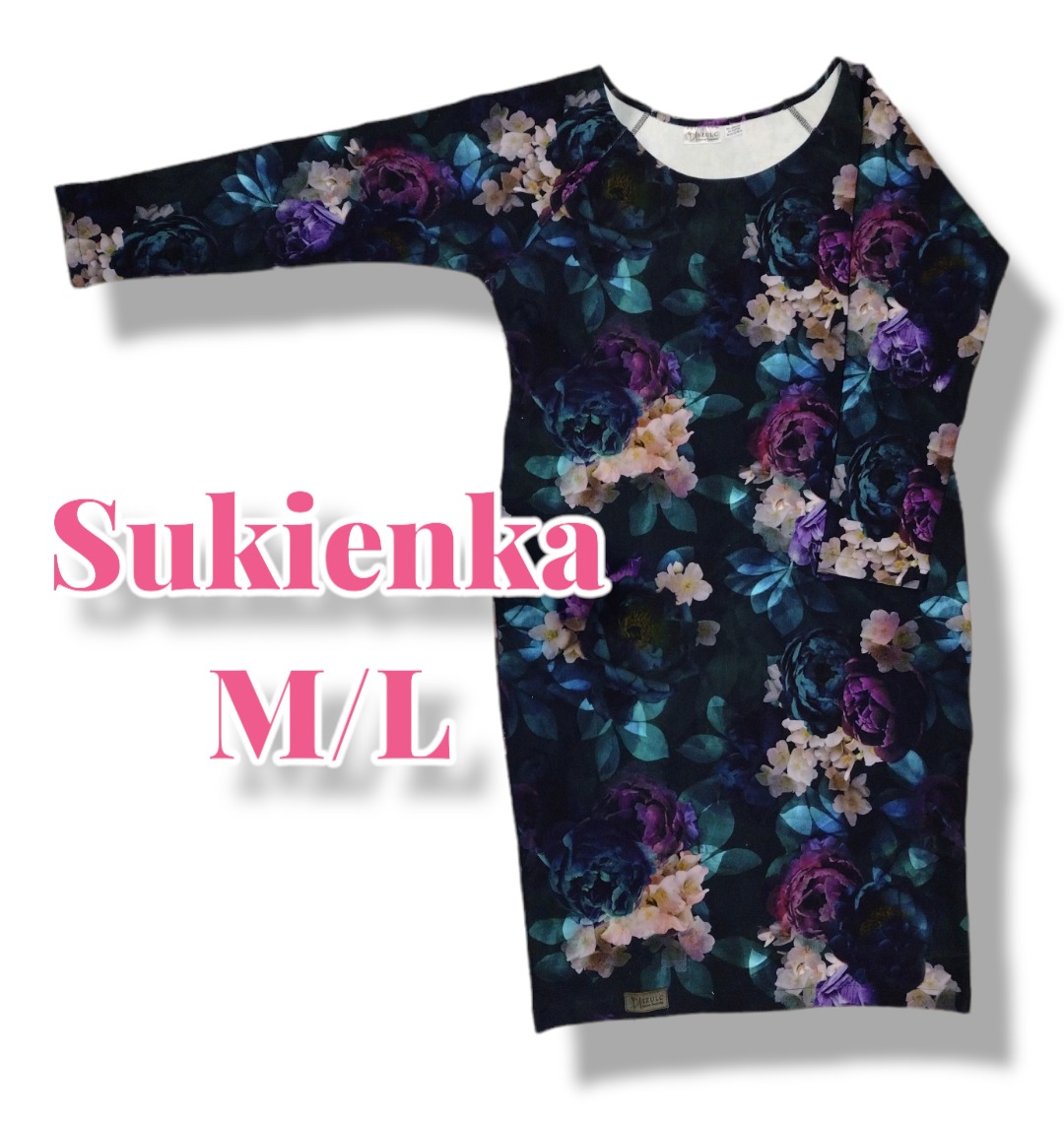 Sukienka damska w rozmiarze M/L z motywem kwiatowym na ciemnym tle, widoczny metka producenta w dolnym rogu.