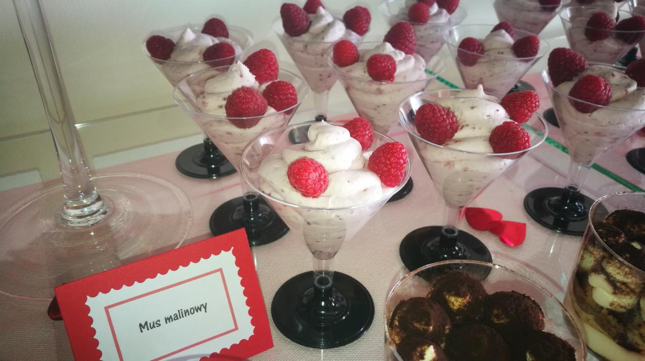 Deser mus malinowy w kieliszkach martini, udekorowany świeżymi malinami, obok deser tiramisu i wizytówka z nazwą deseru.