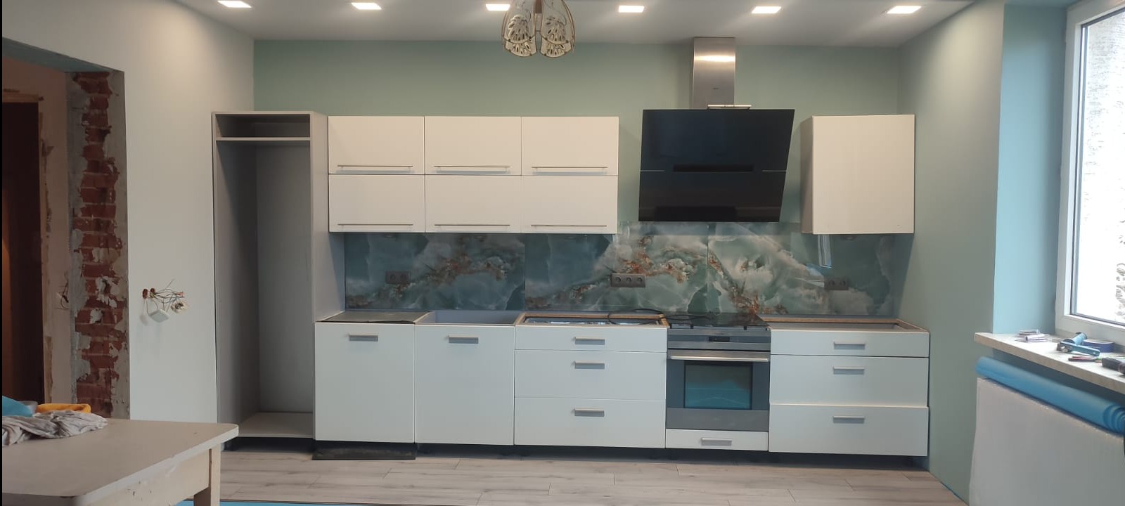 grzejnik ukryty w pasie płytek miedzy szafkami