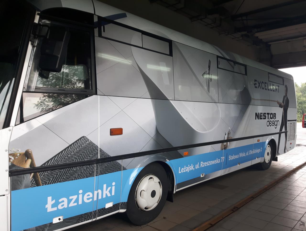 Autobus oklejony reklamą firmy Nestor Design z wizualizacjami łazienek, adresami oddziałów i hasłem 'Excellent'.