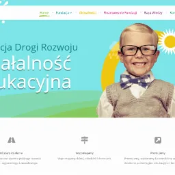 Strona internetowa fundacji edukacyjnej Drogi Rozwoju z uśmiechniętym chłopcem w okularach i muszce na tle błękitnego nieba z żółtym słońcem.