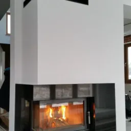 Nowoczesny kominek z czarnym obramowaniem i paleniskiem, widok z boku, instalacja w trakcie wykończenia, Kraków.