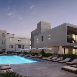 Nowoczesny kompleks apartamentów z basenem oświetlonym od spodu, leżakami i parasolami, widok z poziomu gruntu, wieczorne oświetlenie.