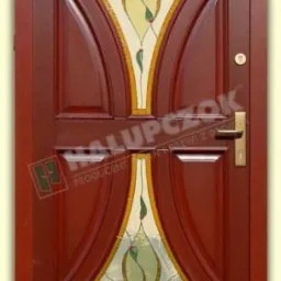 Ciemnobrązowe drzwi zewnętrzne z dekoracyjnym witrażem w kształcie stylizowanych kwiatów, złota klamka, widoczne logo producenta w lewym dolnym rogu.