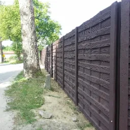 Ogrodzenie betonowe w wzorze 'deska' malowane na ciemny brąz.