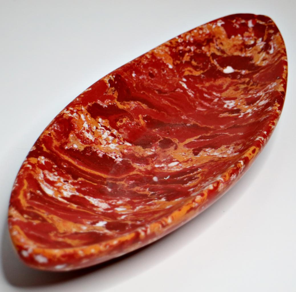 Owalna, dekoracyjna misa z czerwonego marmuru z białymi i pomarańczowymi żyłkami, ustawiona na białym tle.