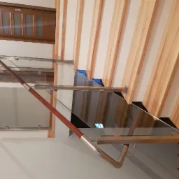 Szklana balustrada z drewnianą poręczą na schodach z drewnianymi panelami ściennymi, widok z dołu.