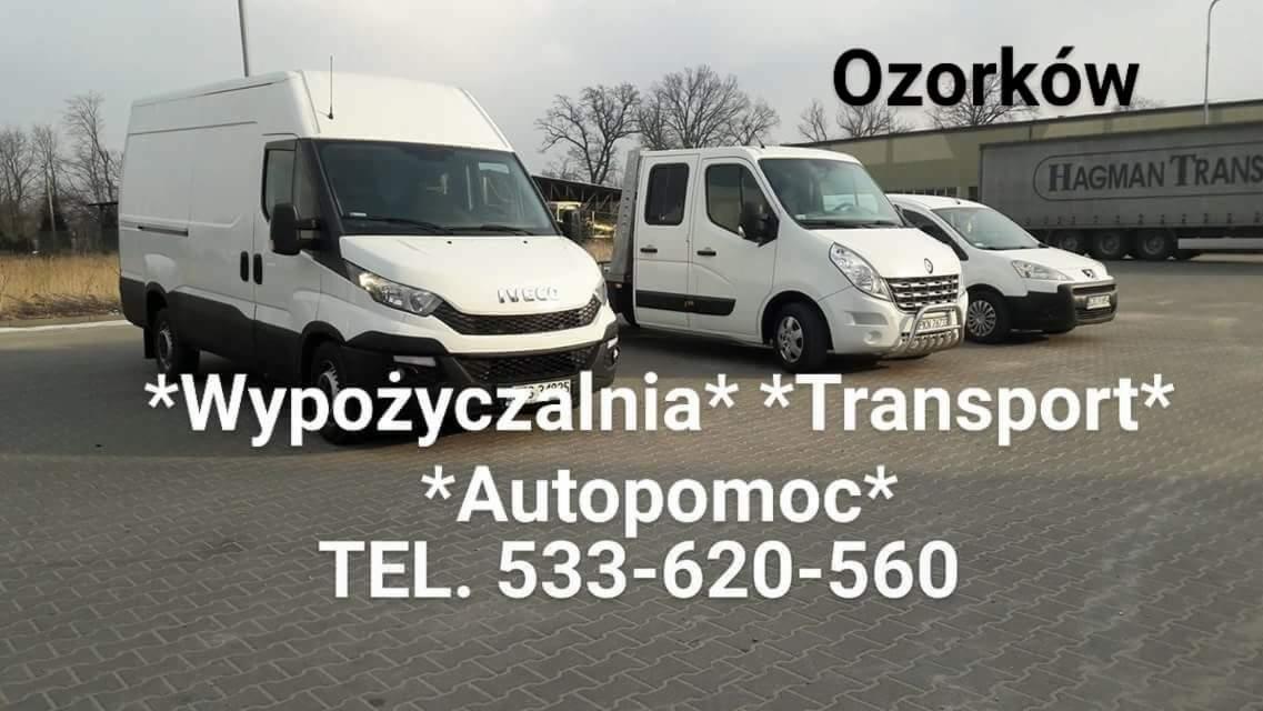 Flota pojazdów: biały Iveco z wysoką zabudową, Renault Master z platformą i Peugeot Partner, zaparkowane na placu firmy transportowej w Ozorkowie, z widocznym tirem w tle i numerem telefonu.