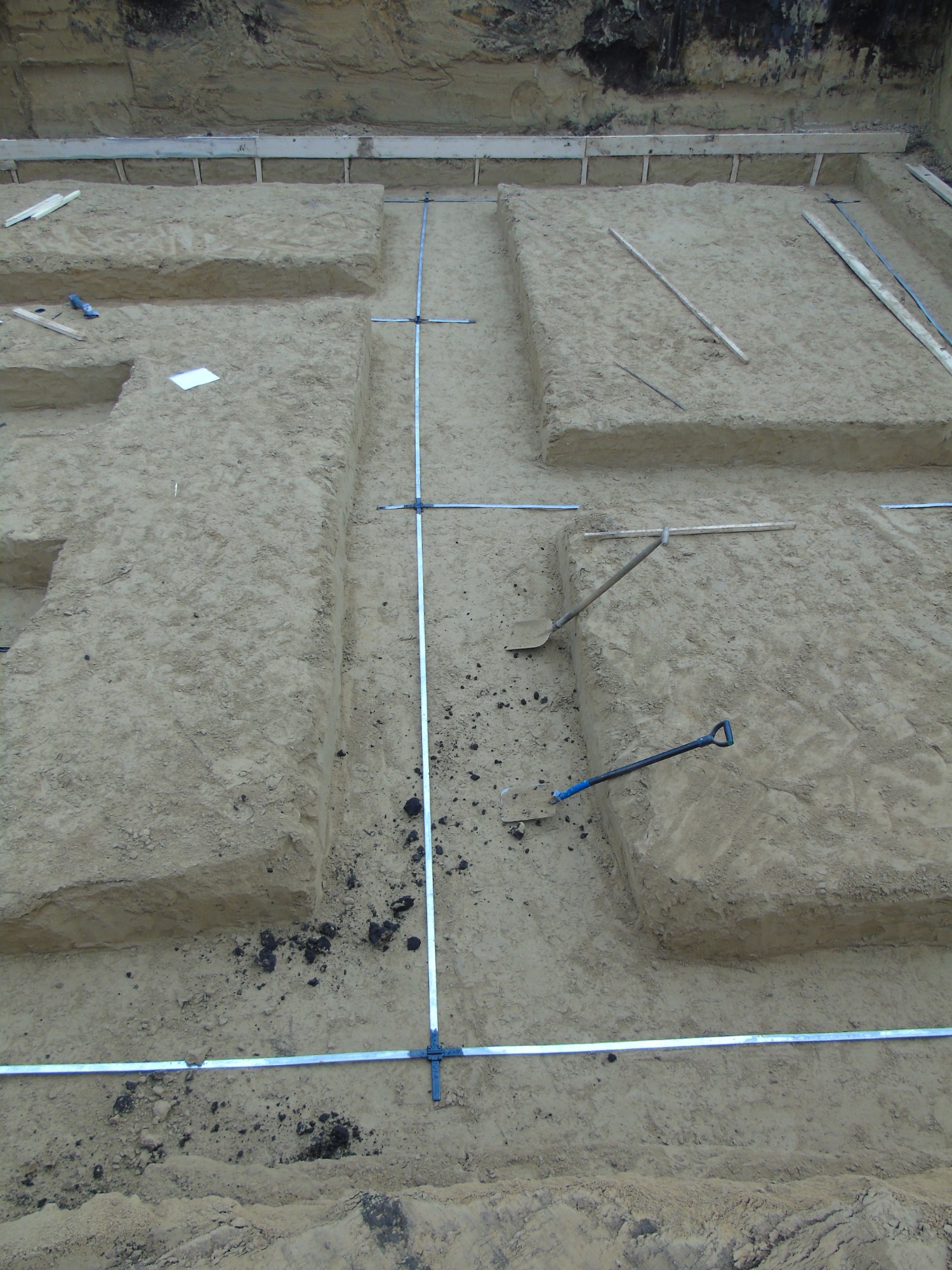 Wykonane wykopy pod fundamenty budynku, widoczne szpadle i wytyczone osie za pomocą poziomicy laserowej.