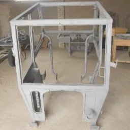 Metalowa rama kabiny pojazdu rolniczego, przygotowana do dalszej obr&oacute;bki, po wstępnym oczyszczeniu i nałożeniu podkładu, widoczne ślady po obr&oacute;bce strumieniowo-ściernej.