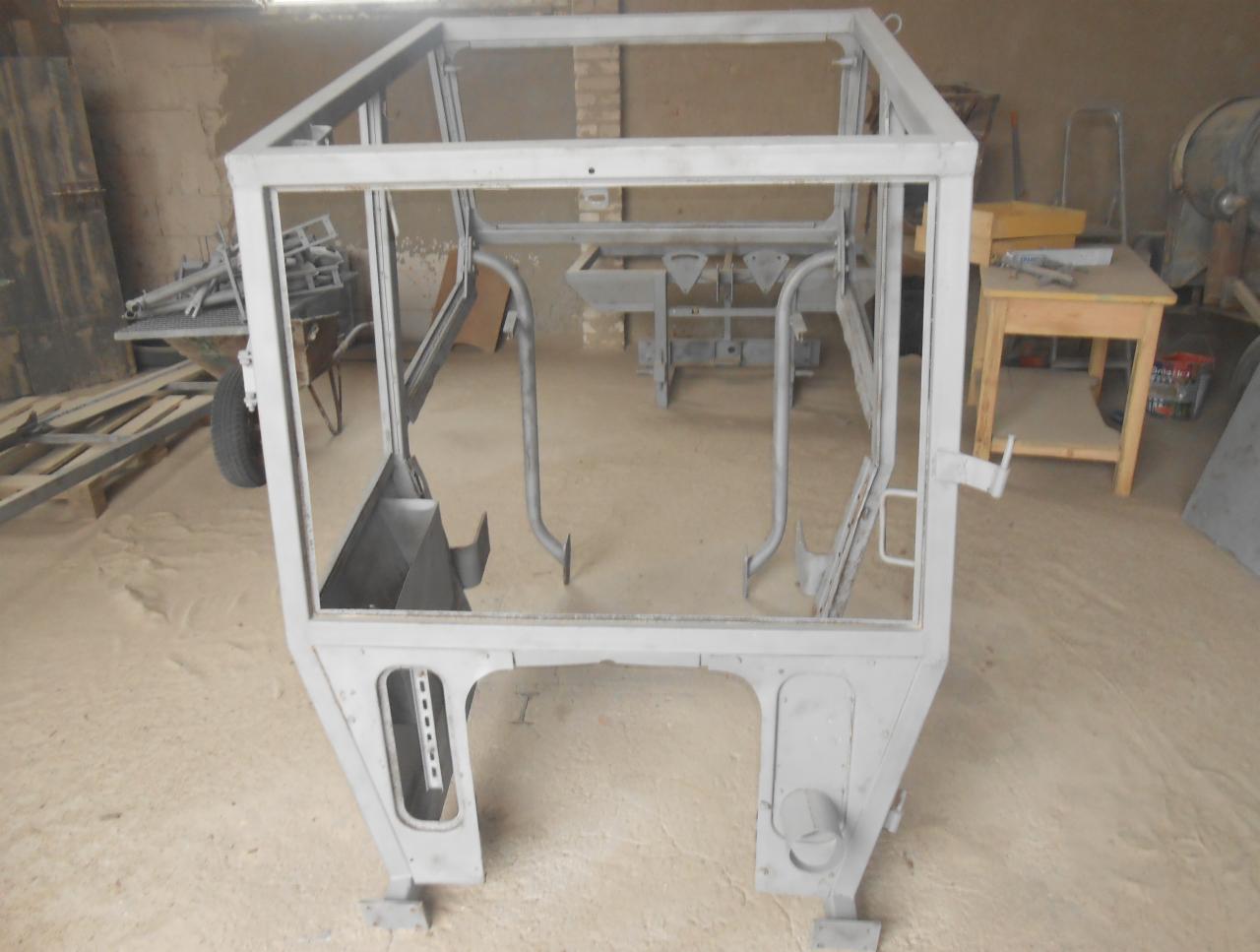 Metalowa rama kabiny pojazdu rolniczego, przygotowana do dalszej obróbki, po wstępnym oczyszczeniu i nałożeniu podkładu, widoczne ślady po obróbce strumieniowo-ściernej.