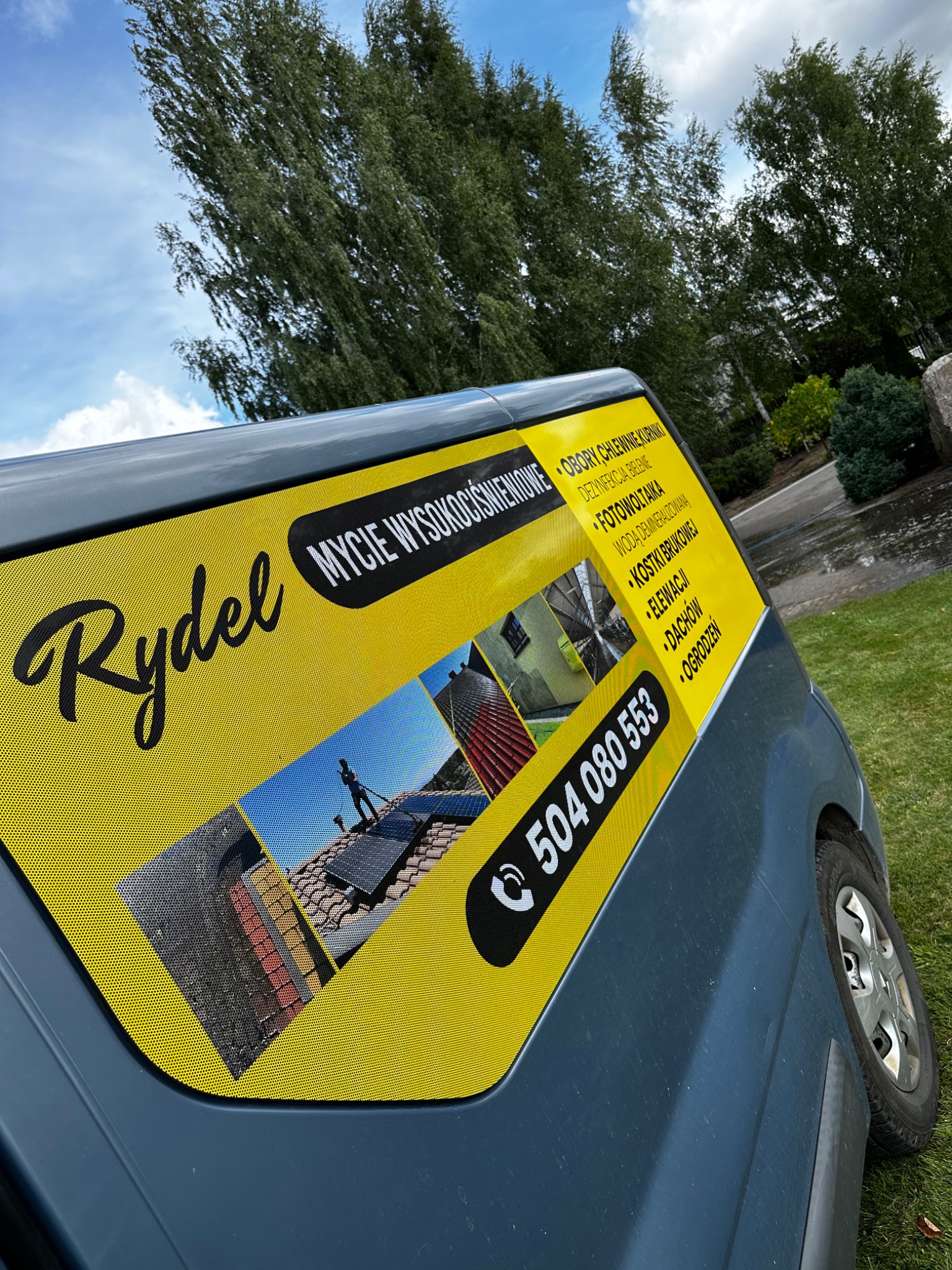 Reklama firmy Rydel na samochodzie dostawczym, oferującej usługi mycia wysokociśnieniowego, w tym fotowoltaiki, kostki brukowej, elewacji, dachów i ogrodzeń, z numerem telefonu.