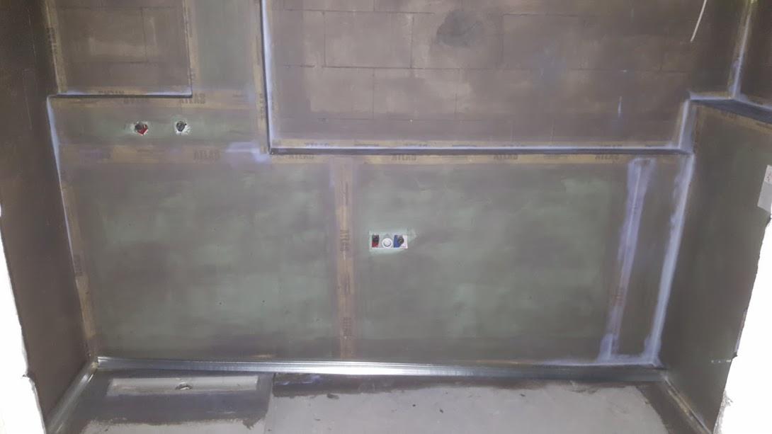 Przygotowanie ścian w łazience do dalszych prac wykończeniowych, widoczne profile montażowe, zabezpieczone narożniki i instalacje elektryczne.