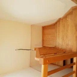 Jasne, drewniane schody z poręczą, widok z dołu, z widoczną strukturą drewna i minimalistycznym oświetleniem.