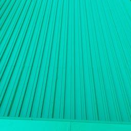 TeamPol - Świeżo pomalowana, karbowana blacha na tarasie w odcieniu jasnej zieleni, widoczna z góry pod kątem.