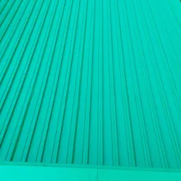 Świeżo pomalowana, karbowana blacha na tarasie w odcieniu jasnej zieleni, widoczna z góry pod kątem.