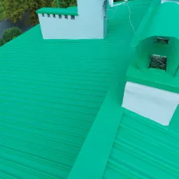 Świeżo pomalowany na zielono blaszany dach z kominem i anteną satelitarną we Wrzosowej, widok z góry.