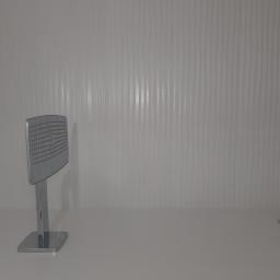 Krzysztof Wojniak - Chromowana deszczownica z kwadratową głowicą i minimalistyczna bateria umywalkowa na tle białej ściany z falistą strukturą.