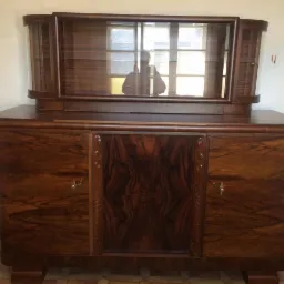 Antyczny, fornirowany kredens z nadstawką witrynową, widoczny wzór słojów drewna i metalowe kluczyki.