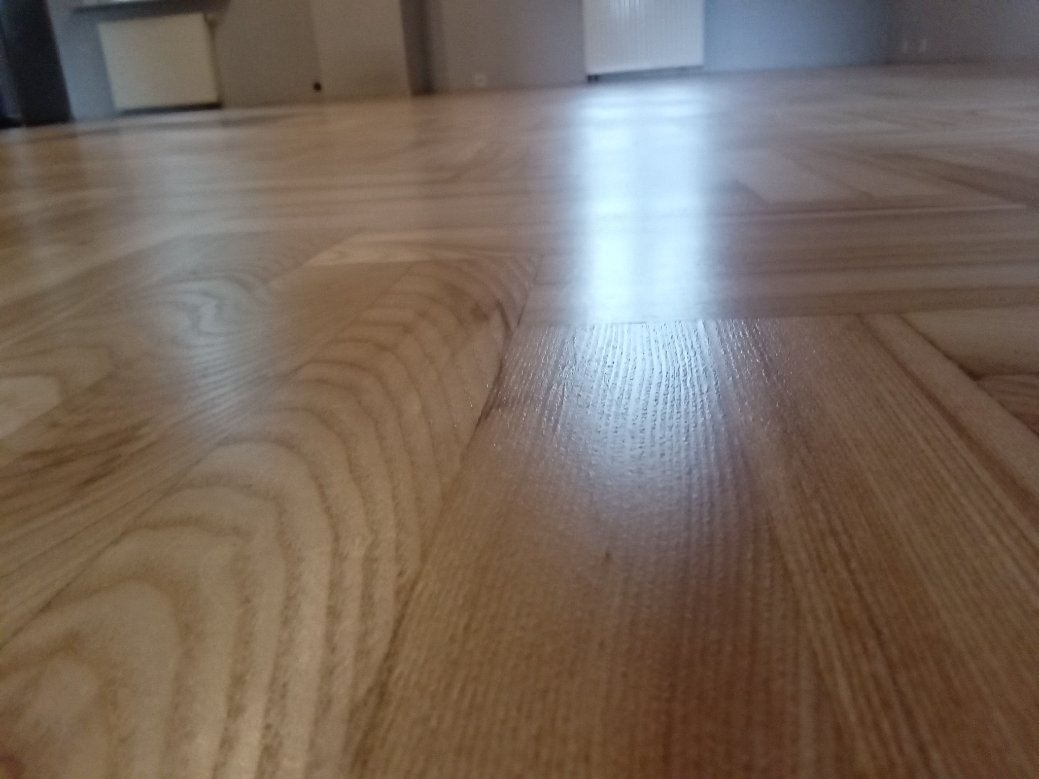 Parkiet ułożony w jodełkę, po renowacji, widoczne delikatne refleksy światła.