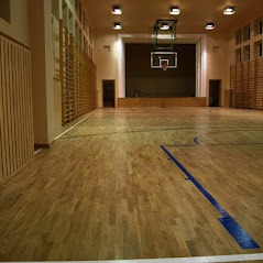 Parkiet w sali gimnastycznej po renowacji, widoczne linie boiska i odnowiona powierzchnia drewna.