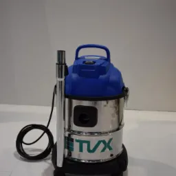 Profesjonalny odkurzacz przemysłowy marki TVX, z chromowanym zbiornikiem i niebieską pokrywą, stojący na białej, błyszczącej podłodze.