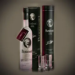 Butelka wódki z portretem Paderewskiego, pudełko i kieliszki na ciemnym tle.