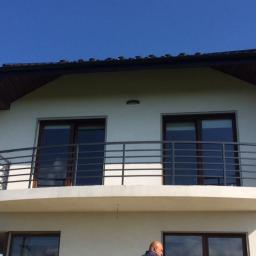 Szat-Com - Balkon z prostą, metalową konstrukcją zabezpieczającą w Tarnowie, widok z dołu, jasne niebo w tle.