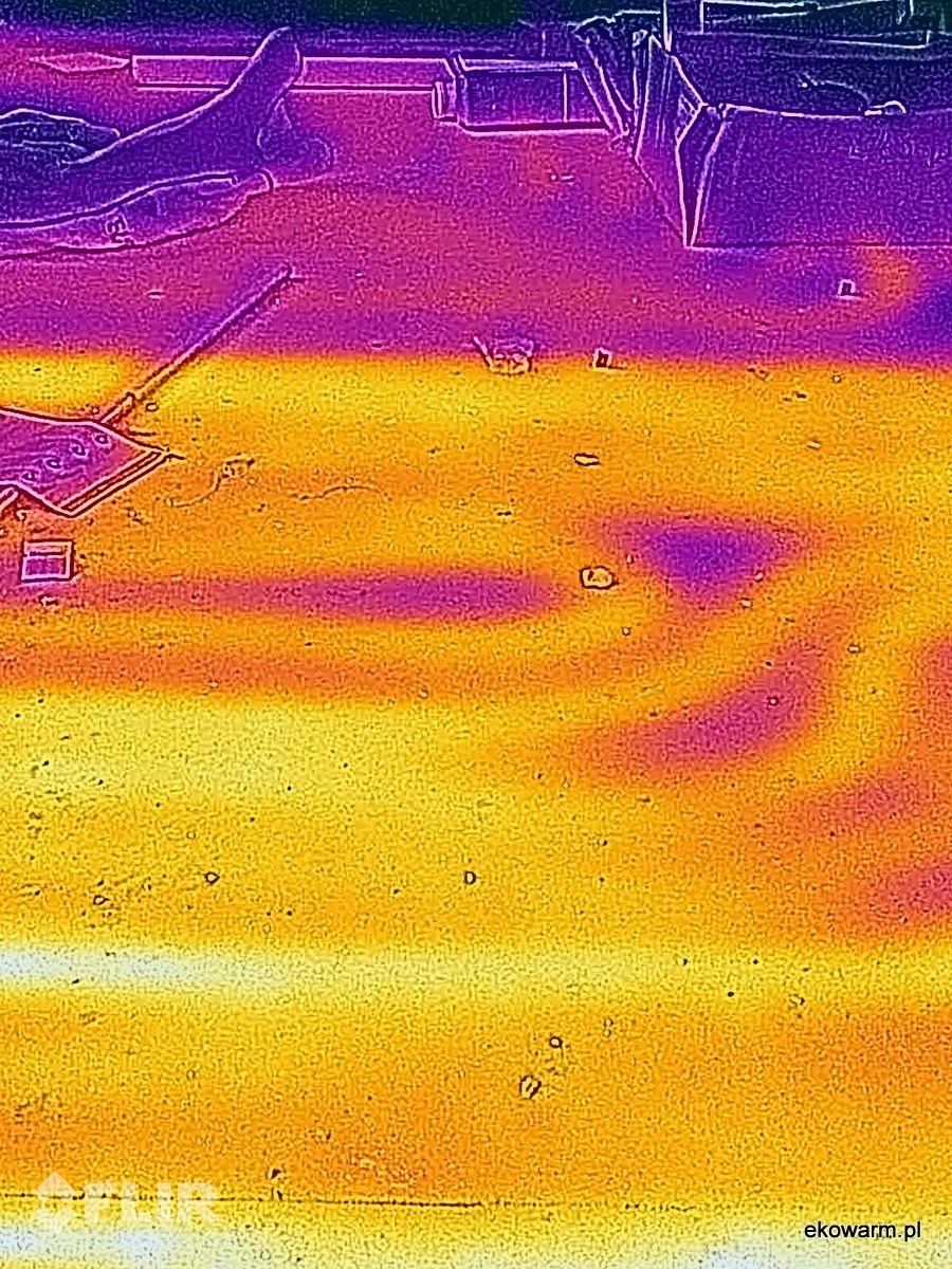 Termowizyjne zdjęcie podłogówki w trakcie wykonywania, z widocznymi rurami i elementami montażowymi, przedstawione w skali barw od fioletu do żółci.